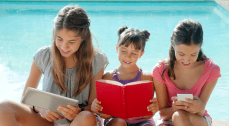 3 jeunes filles en train de lire au bord d'une piscine