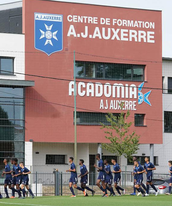 Centre de formation A.J. Auxerre partenaire d'Acadomia, bâtiment du centre et jeunes footballeurs en entrainement devant